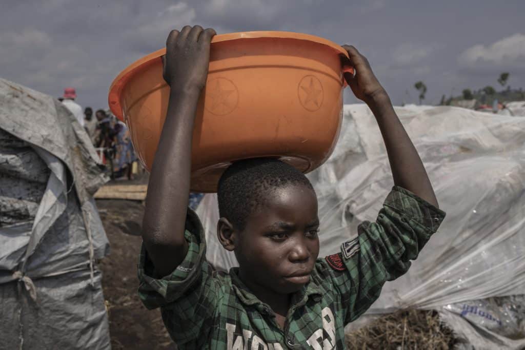 Merci Shivima, 12 ans, transporte une bassine d'eau dans le camp de déplacés de Bulengo, dans l'est de la République démocratique Congo, le 08 février 2023. © UNICEF/UN0791491/Ndebo