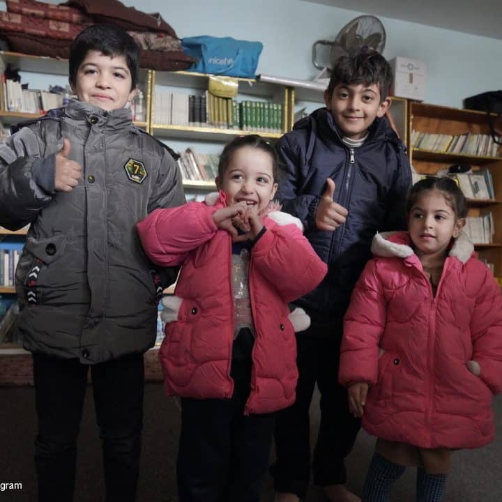 Le 13 janvier 2024, des enfants posent pour une photo au Centre des femmes de Rafah, dans le sud de Gaza, actuellement utilisé comme abri, après la distribution de manteaux d'hiver, achetés par l'UNICEF et distribués par ses partenaires. © UNICEF/UNI502760/Ingram