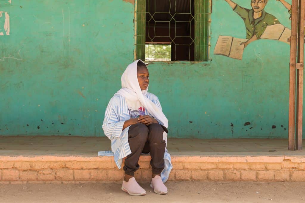 Walaa, 15 ans, est assise sur la véranda d'une salle de classe de l'espace d'apprentissage sécurisé d'Alshargia, soutenu par l'UNICEF, dans l'État de Kassala.© UNICEF/UNI546813/Elfatih
