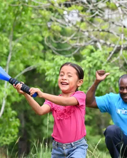 Un membre du personnel de l'UNICEF joue au baseball avec Oneida, 5 ans, dans le village d'Otoxha, au sud du Belize. Sur place, l'UNICEF a mis en place un programme de protection sociale. © UNICEF/UNI594461/Dejongh