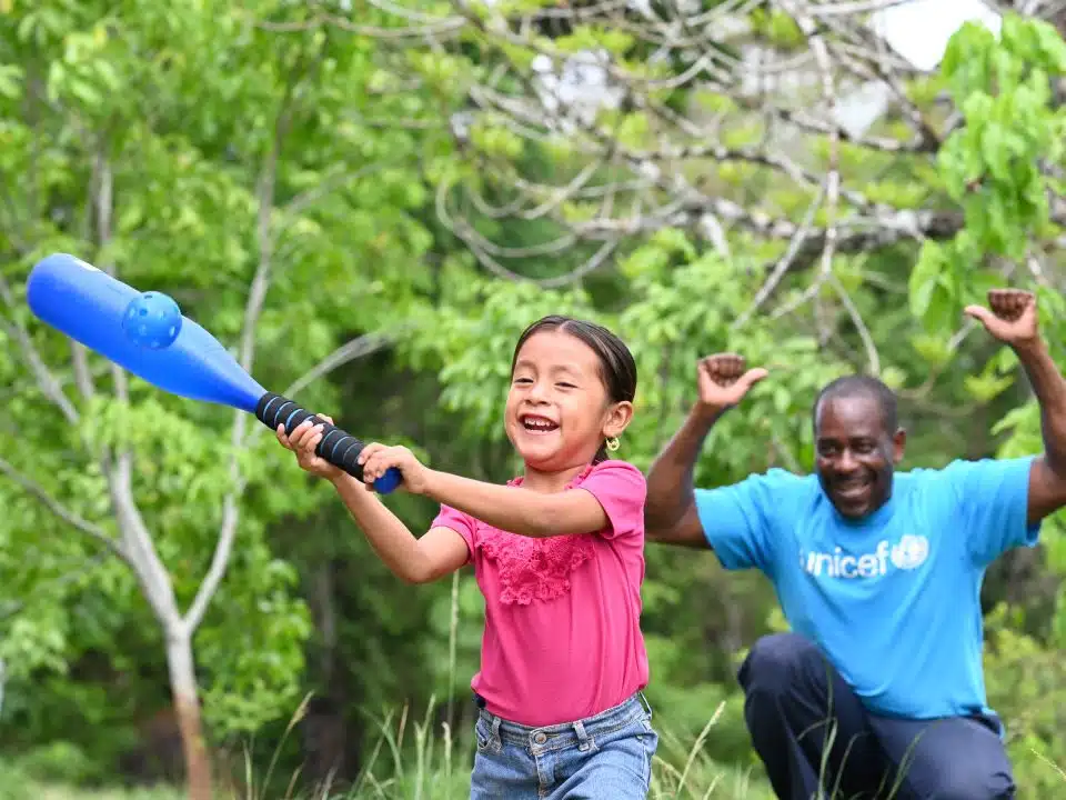 Un membre du personnel de l'UNICEF joue au baseball avec Oneida, 5 ans, dans le village d'Otoxha, au sud du Belize. Sur place, l'UNICEF a mis en place un programme de protection sociale. © UNICEF/UNI594461/Dejongh